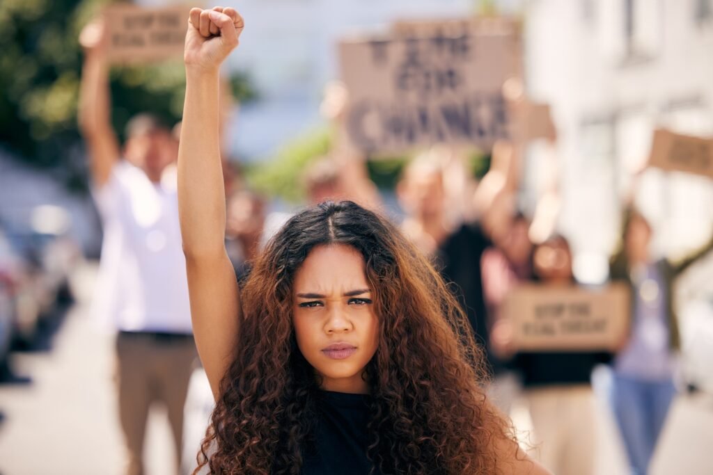 Shot of a young female protester at a rally with her fist raised